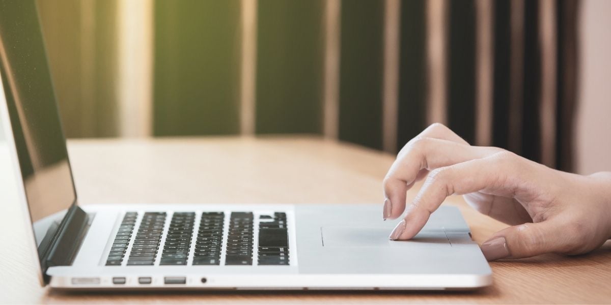 A woman clicking on an ad on her laptop, representing last AdWords click attribution