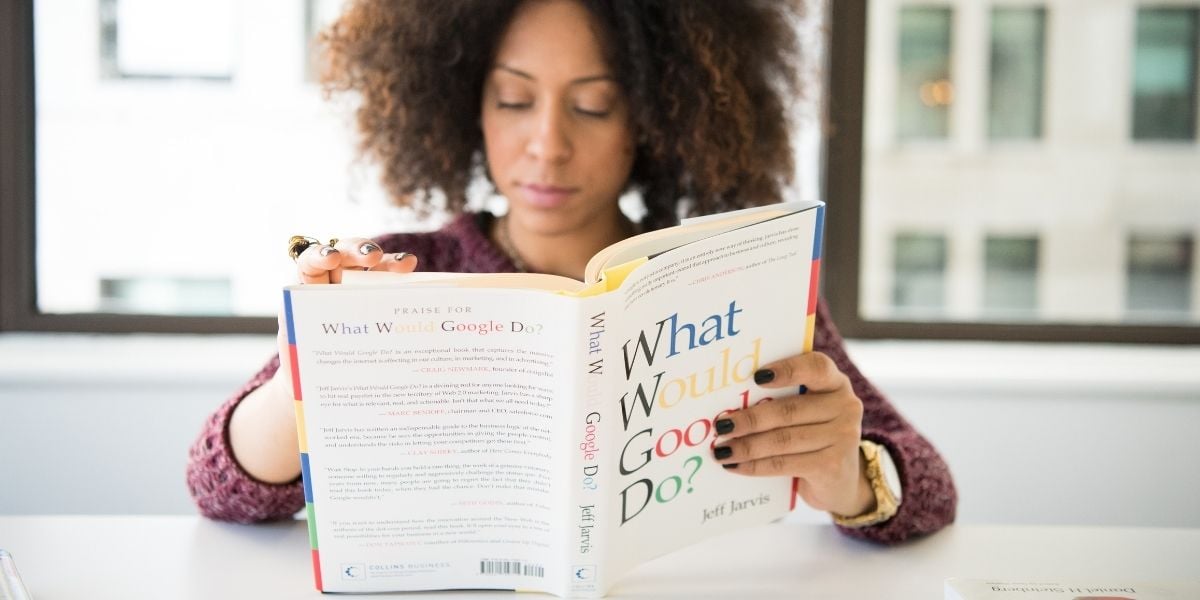 A woman reading a book on Google, signifying a need to research how to overcome SMB digital marketing challenges related to search engine marketing