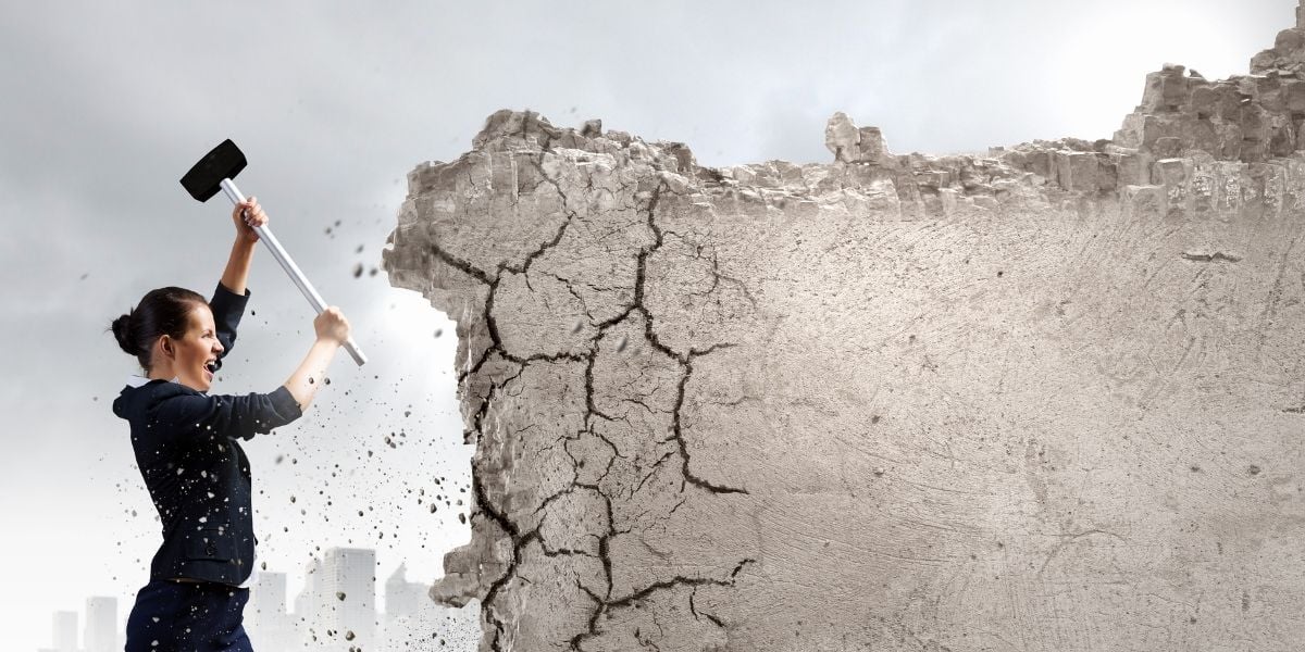 A business woman smashing a wall with a rubber mallet, signifying her overcoming SMB digital marketing challenges