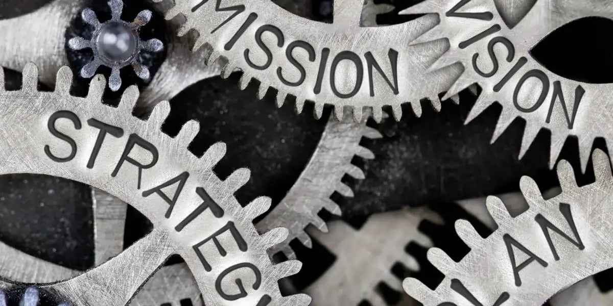 Close up of interlocking gears labeled strategy, mission, and plan representing social media marketing planning