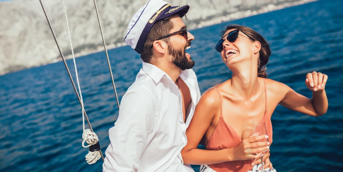 A couple wearing luxury brands and laughing on a boat.