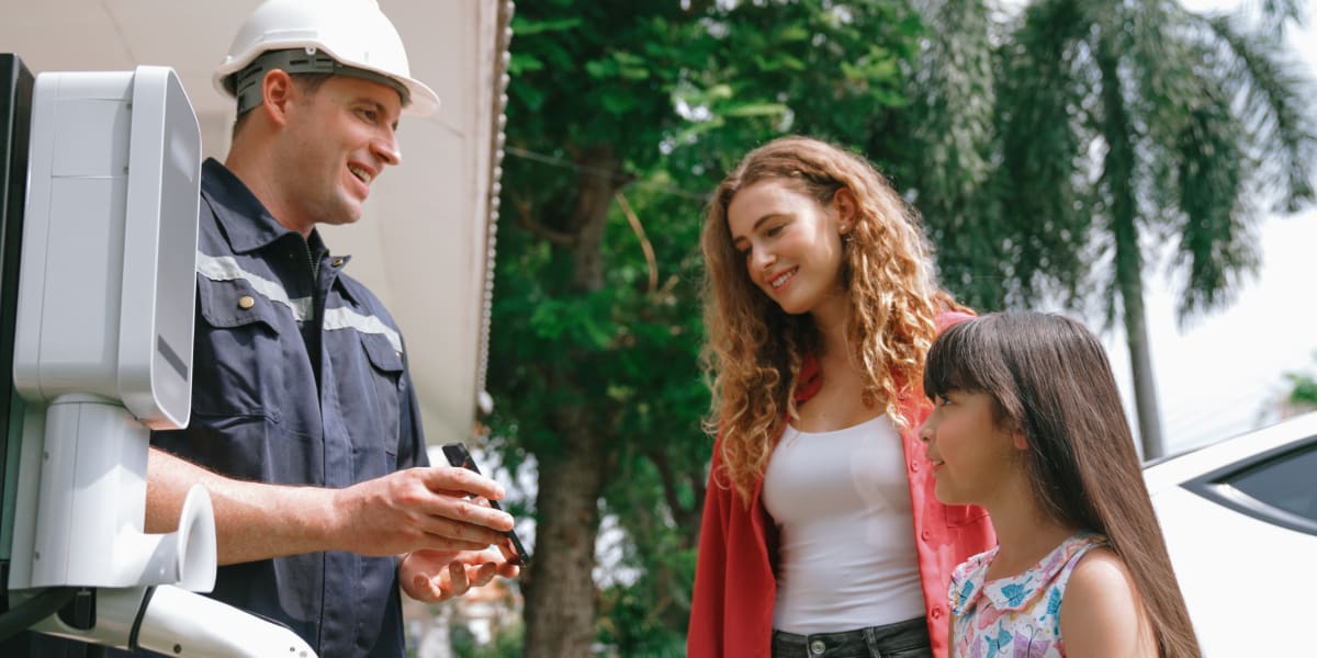 Electrician showing device to a smiling woman and child, representing seo for electricians helping reach local residential customers
